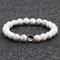 Detail of white marble stone beads with yin yang metal charm on textured black background - White Turquoise Bracelet
