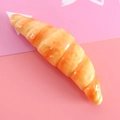 Creative croissant-shaped ballpoint pen with realistic golden finish on pink background - Croissant