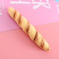 Novelty baguette-shaped ballpoint pen with realistic bread texture on a pink mat - Baguette