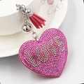 Herz-Schlüsselanhänger mit LOVE-Strasssteinen und Quaste an einer weißen Porzellantasse - Rosa