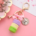 Pastel macaron keychain with pink bow and Eiffel Tower charm on pink background - Purple & Yellow