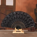 Elegant black folding fan with sequins and golden carved ribs on wooden base display - Black