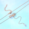 Rose gold bow necklace with sparkling crystals and drop pendant on light blue background - Bow Necklace (Non-adjustable) / Rose Gold