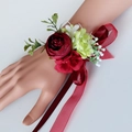 Wedding wrist corsage with burgundy rose, green leaves and ribbon on a mannequin hand - Vintage Red Wrist Flower