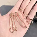 Set of four gold safety pins with polished metallic finish held in hand - Gold