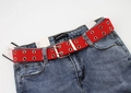 Dettaglio della cintura in tela rossa con doppi occhielli abbinata a jeans blu - Rosso