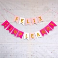 Pink and gold Spanish Feliz Cumpleaños birthday banner on a white brick background - Rose Pink White Happy Birthday