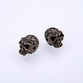 Macro shot of two bronze skull-shaped beads for DIY jewelry making with hole detail - Cyan Bronze