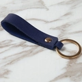 Portachiavi in pelle blu scuro con texture litchi e anello in ottone su marmo - Blu