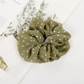 Dettaglio del tessuto dell'elastico scrunchie verde scuro a pois su sfondo di un libro - Pois / Verde