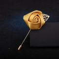 Golden satin rose brooch with metallic leaves and long pin on black background - Turmeric