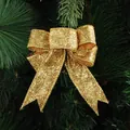 Fiocco di Natale dorato con glitter appeso a un ramo di pino per decorazione festiva - Oro