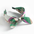 Close-up of fabric headband with colorful vintage pattern and bow detail on white base - Green Chain Bow
