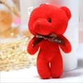 Macro detail of a red plush teddy bear keychain with a Love printed brown ribbon - Red