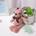 Pink handmade crochet teddy bear plush toy with brown bow in a cozy setting - Korean Pink