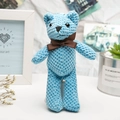 Handmade blue knitted bear plush toy with brown bow tie on cozy desktop background - Blue