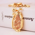 Golden golf bag keychain featuring champagne crystals and mini clubs on white background - Peach