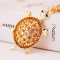 Portachiavi tartaruga dorata con strass ambrati scintillanti su libro bianco - Oro