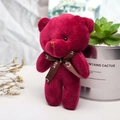 Primo piano di un piccolo orsetto di peluche rosso con nastro decorativo love - Borgogna