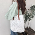 Close-up of white floral lace tote bag with brown leather strap worn by a model - White