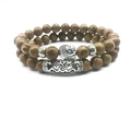 Detailed macro view of Buddha head and etched silver tube on natural stone beads - Jasper