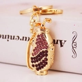 Golden golf bag keychain with purple rhinestones on white book background - Purple