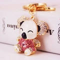 Simpatico portachiavi koala dorato con strass rosa e orecchie bianche su sfondo libro - Rosa