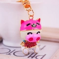 Pink cartoon pig keychain with sparkling crystals and golden metal links on a white background - Pink