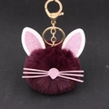 Close-up of deep purple plush ball keychain with glitter cat ears and gold clasp - Purplish Red