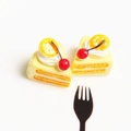 Detailopname van twee miniatuur hars gebakjes met kersen en citroen versiering - Gele Kersentaart