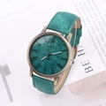 Retro bronze watch with green denim texture strap and Roman numeral dial on a desk - Green