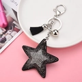 Dettaglio portachiavi a stella con strass, nappa nera e accessorio campanello argento - Canna di fucile