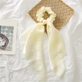 Close-up van een crème satijnen scrunchie met lange linten op decoratieve achtergrond - Beige