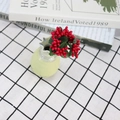 Artificial red berry stems in a light green ceramic vase on a checkered tablecloth - Red