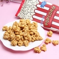 Ciondoli in resina popcorn su piatto bianco con sacchetto a righe rosse su sfondo rosa - Giallo Caramello Misto