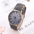 Macro detail of bronze quartz watch featuring grey denim texture and Roman numerals - Black and Gray