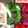 Macro view of laser-cut heart candy boxes with satin ribbons and pearlescent finish - Reflective Green