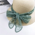 Cappello di paglia beige con fiocco in pizzo ricamato verde su un tavolo bianco pulito - Verde