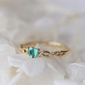 Dettaglio macro di anello con cuore smeraldo e fascia infinito su petali bianchi - US 6 / Oro Verde Zirconia