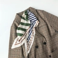 Dettaglio di un foulard plissettato in seta con motivi geometrici a righe colorate - Verde