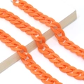 Macro view of bright orange acrylic thick chain link strap accessory on a white book - Bright Orange