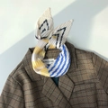 Dettaglio di un foulard in seta a pieghe con motivo a zigzag giallo e blu su un blazer - Giallo