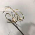 Close-up of golden spiral drop earrings with white pearl detail on a jewelry card - 925 Silver Post Style