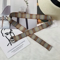 Detail of plaid nylon canvas belt with silver double D-ring buckle on plush background - Light Coffee