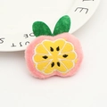 Accessoire cheveux en peluche rose forme fruit avec broderie sur une assiette blanche - Orange