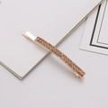 Detailed close-up of a golden hair clip with two rows of sparkling champagne rhinestones - Champagne
