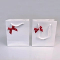 Detailed view of two white paper gift bags with red crystal jewelry ribbons and rope handles - Bowknot Gift Bag / White