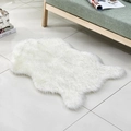 White faux fur animal skin rug placed on a tile floor next to a modern sofa - White with Grey Tips