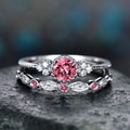 Macro shot of two-piece sterling silver ring set with round pink stone and diamond halo - Red