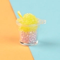 Macro shot of miniature luminous smoothie cup with yellow crushed ice and pink beads inside - Yellow
